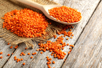 Red lentils in the wooden spoon on a grey wooden table