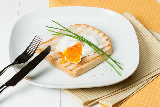Poached Egg On Toast With Chives And Spices. White Plate