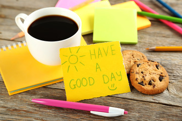 Piece of note paper with cup of coffee and cookies on grey woode