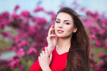 Happy beautiful young woman in blossom park with trees and flowers. 