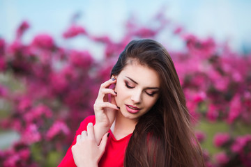 Happy beautiful young woman in blossom park with trees and flowers. 