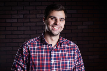 Fototapeta premium Portrait of cute funny young guy in a plaid shirt/ Cute young guy in a plaid shirt smiling