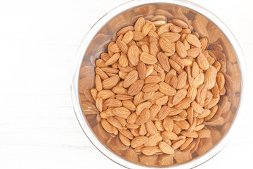 Almonds in a bowl on white wooden background