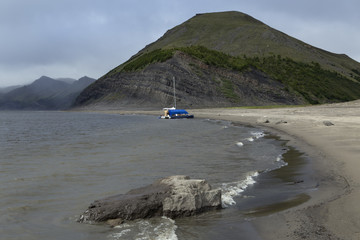 Beach of the great river and the catamaran under the mountain. Lena river. Yakutia. Russia.