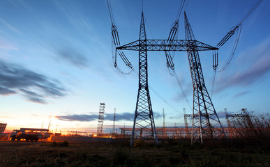 electricity transmission pylon silhouetted against blue sky at d