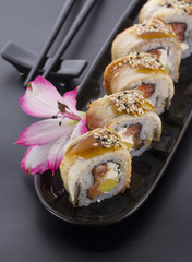 Eel sushi roll on a black plate with flower decoration
