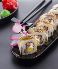 Eel sushi roll on a black plate with flower decoration