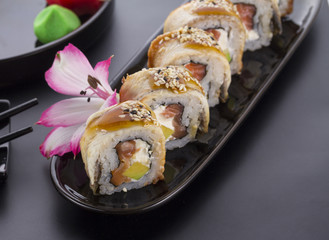 Eel sushi roll on a black plate with flower decoration