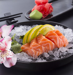 Salmon raw sasimi with ice on a black background