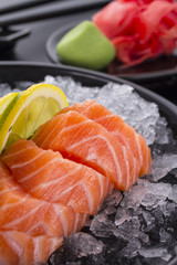 Salmon raw sasimi with ice on a black background