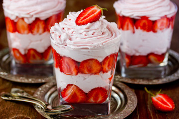Strawberry with whipped cream in a glass. Gourmet dessert with fresh summer berries and lush cream, selective focus