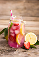 Homemade fresh pink lemonade with lemon, lime and strawberries