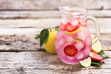 Homemade fresh pink lemonade with lemon, lime and strawberries