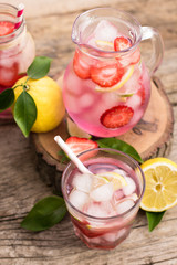 Homemade fresh pink lemonade with lemon, lime and strawberries