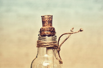 Obraz na płótnie Canvas vintage glass bottle with a cork and rope. in such bottles used to put notes with messages and throw it into the sea. work of art handmade