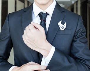 Businessman with spanner in suit pocket.

