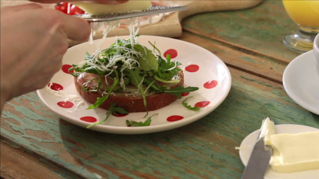 woman grating chease on to a healthy sandwich