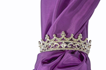 Silberne Krone mit feinem lila Stoff freigestellt auf weißem Hintergrund