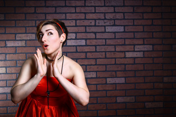 Portrait of surprised beautiful woman in a red dress/ Portrait of surprised beautiful woman in a red dress against a brick wall