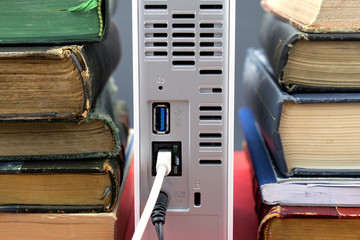 Several old books on a bookshelf together with a high capacity network hard drive symbolizing new...