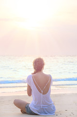 Fototapeta na wymiar woman practicing yoga at sunrise beach