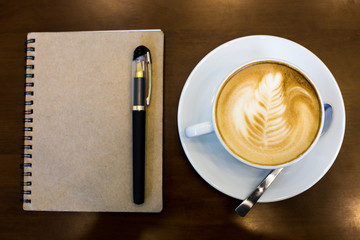 Coffee cup and notebook on table background.