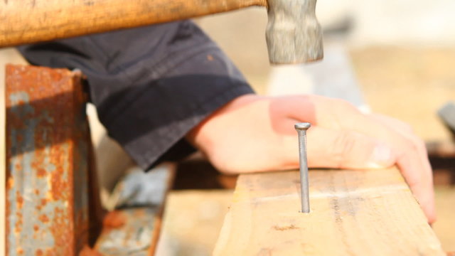 man hammers a nail into a plank, close-up