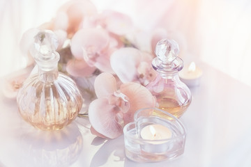 Perfume and aromatic oils bottles surrounded by flowers and cand