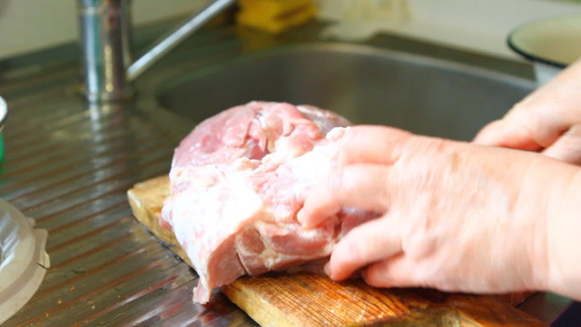 Woman cut pork meat on a cutting board, closeup