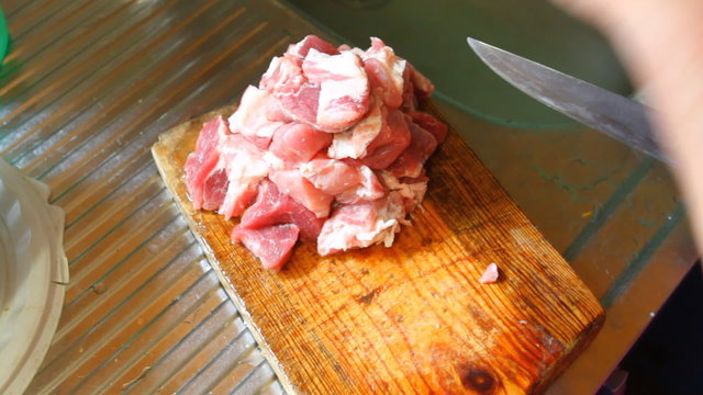 Woman cut pork meat on a cutting board, closeup