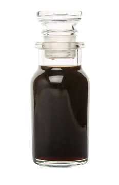 Italian balsamic vinegar in glass vial over wooden background