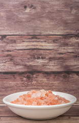Himalaya or Himalayan rock salt in wooden bowl over wooden background