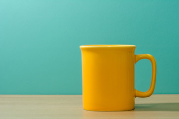yellow mug on wooden table with green background