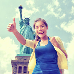 Happy Asian Chinese tourist doing thumbs up having fun visiting the Statue of Liberty, american...