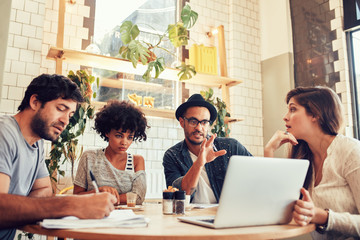 Creative business team at a coffee shop with laptop