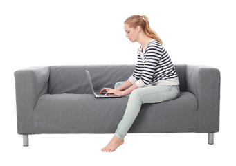 Obraz premium a pretty blonde lady wearing casual clothes, lounging on a grey sofa. isolated on a white background.