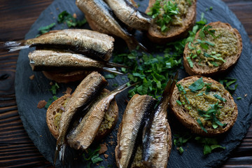 Smoked sprats served with basil pesto and parsley on brown bread