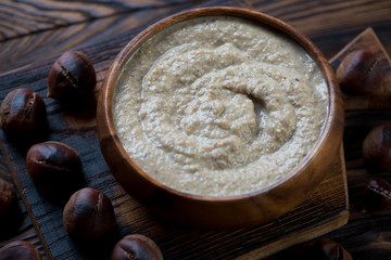 Wooden bowl with chestnut cream-soup, studio shot, closeup