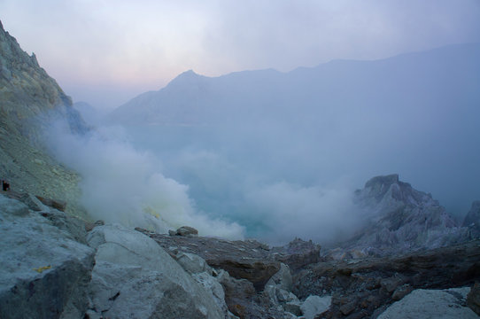 Ijen volcano in East Java contains the world's largest acidic volcanic crater lake, called Kawah Ijen, spewing out sulphur smoke in the morning. Sun is hidden in mist.
