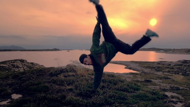 Man doing capoeira at sunset on the top of a mountain in Norway
