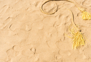 Old weathered yellow nylon rope on the sand