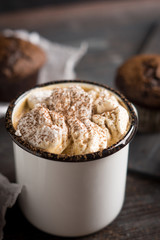 Cup of hot cocoa with marshmallows and chocolate muffins on the dark rustic wooden background