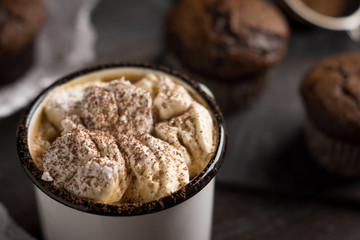 Cup of hot cocoa with marshmallows and chocolate muffins on the dark rustic wooden background