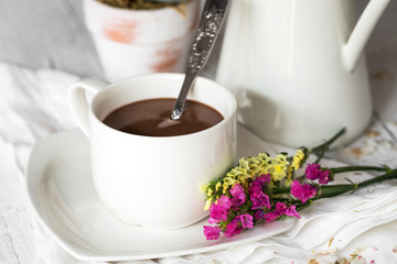 Still life of flowers in jar and cup with spoon