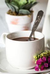 Still life of flowers in jar and cup with spoon