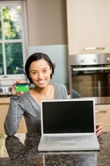 Smiling brunette showing laptop and credit card