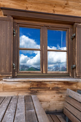 Berglandschaft spiegelt sich im Fenster einer Berghütte 