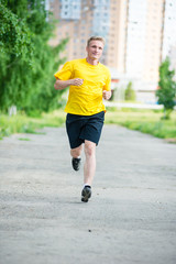 Sporty man jogging in city street park. Outdoor fitness.
