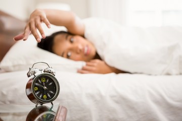 Obraz na płótnie Canvas Alarm clock against brunette on bed