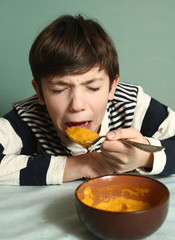  boy eat pumpkin soup with expression of disgust